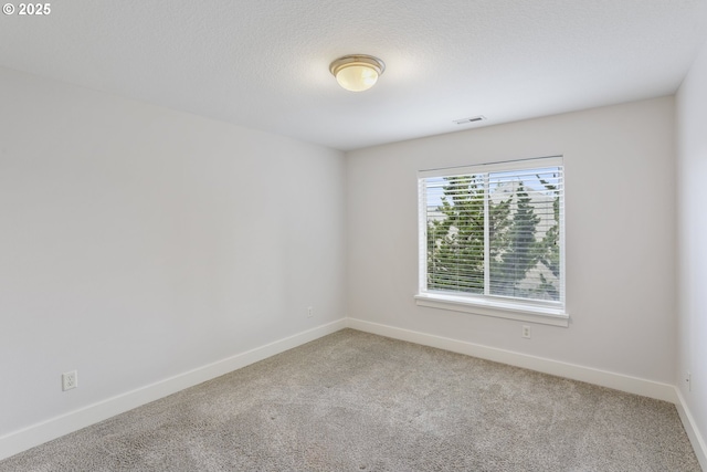 unfurnished room featuring carpet floors, baseboards, visible vents, and a textured ceiling