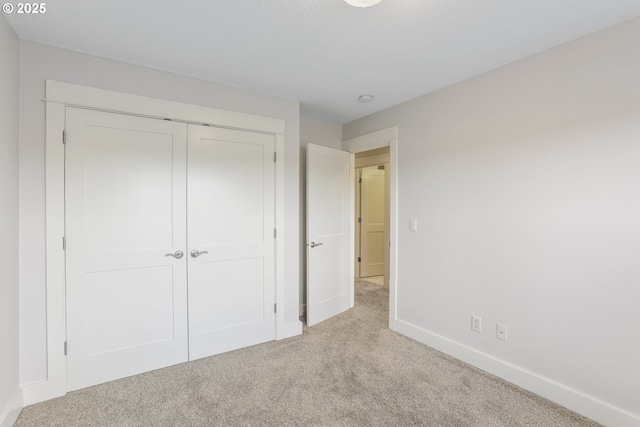 unfurnished bedroom with carpet, baseboards, and a closet