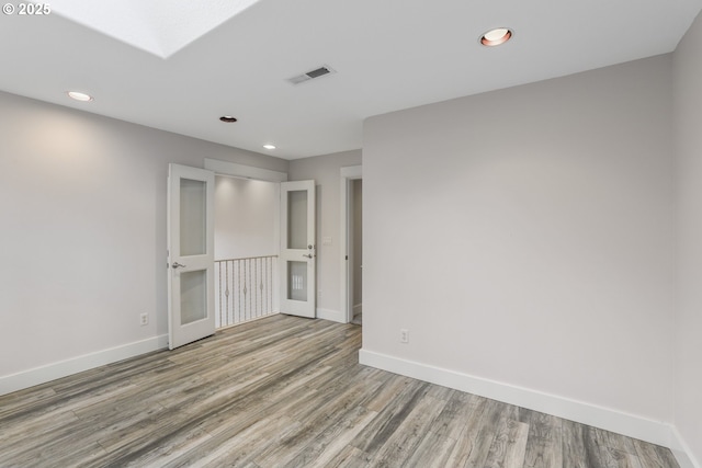 unfurnished room featuring recessed lighting, wood finished floors, and baseboards