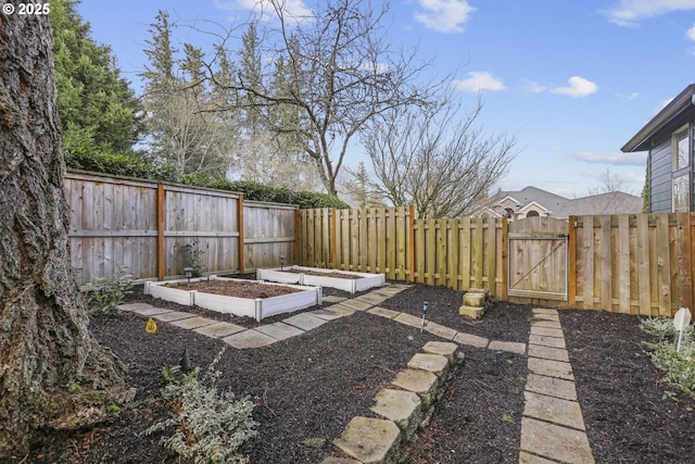 view of yard with a gate, a fenced backyard, and a vegetable garden