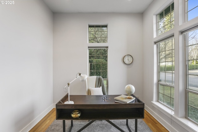 office area with baseboards, wood finished floors, and a healthy amount of sunlight