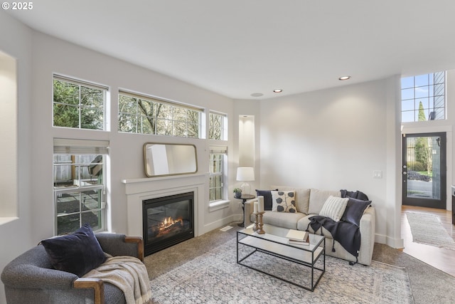 living area featuring a glass covered fireplace, carpet flooring, baseboards, and recessed lighting