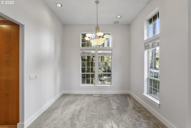 unfurnished dining area with carpet floors, recessed lighting, an inviting chandelier, and baseboards