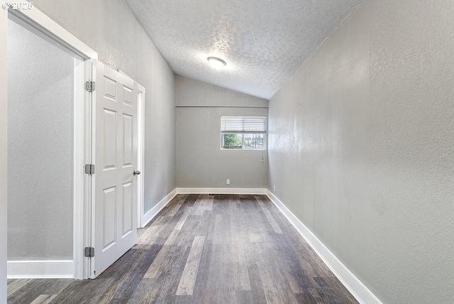 13616 SE Rhine St, Portland, OR 97236 - empty room featuring a textured ceiling, dark wood-style floors, vaulted ceiling, a textured wall, and baseboards
