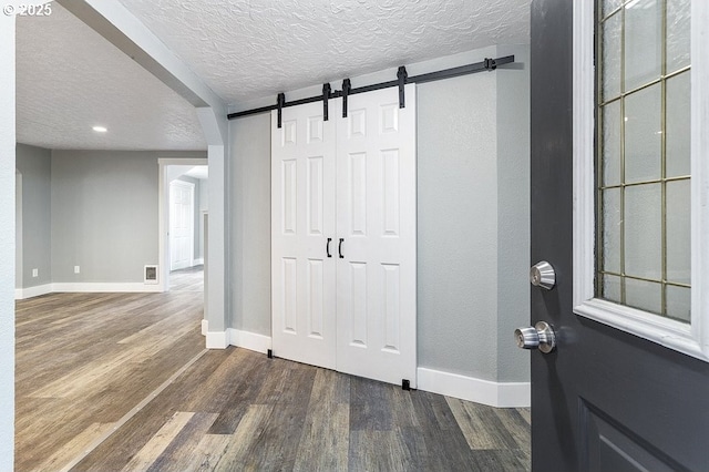 13616 SE Rhine St, Portland, OR 97236 - foyer entrance with baseboards, dark wood finished floors, a barn door, a textured ceiling, and recessed lighting