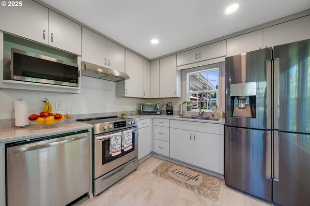 kitchen featuring appliances with stainless steel finishes, light countertops, a toaster, a sink, and under cabinet range hood