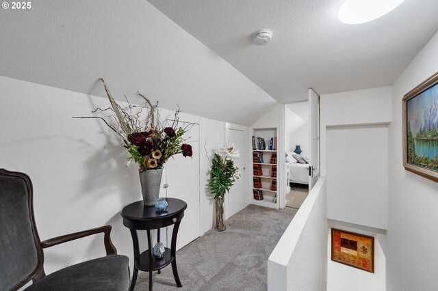 hallway with carpet floors and vaulted ceiling