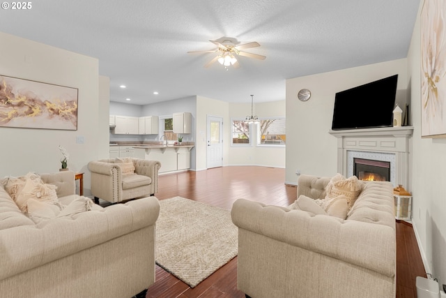 11769 SW 129th Pl, Tigard, OR 97223 - living room featuring dark wood-type flooring, a ceiling fan, recessed lighting, a warm lit fireplace, and baseboards