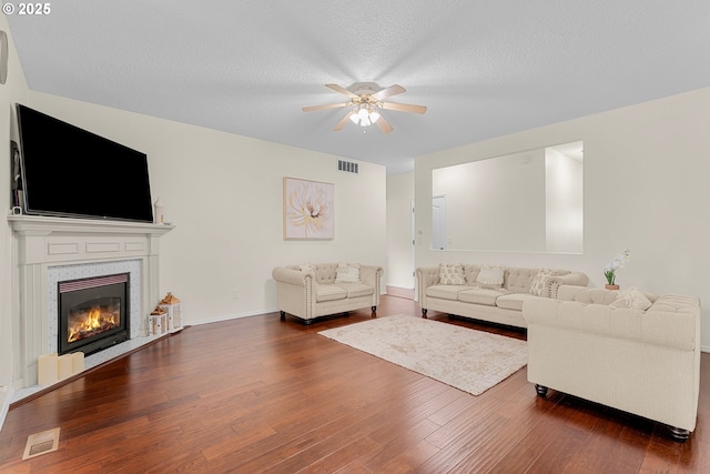 11769 SW 129th Pl, Tigard, OR 97223 - living area featuring a ceiling fan, dark wood-style flooring, baseboards, a glass covered fireplace, and a textured ceiling