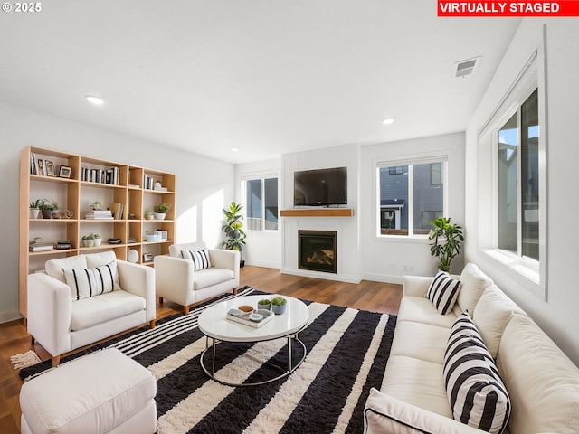 living room with recessed lighting, visible vents, wood finished floors, and a glass covered fireplace