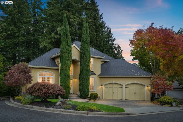 16555 SW Red Rock Ct, Beaverton, OR 97007 - view of front facade with stucco siding, a garage, a shingled roof, and driveway