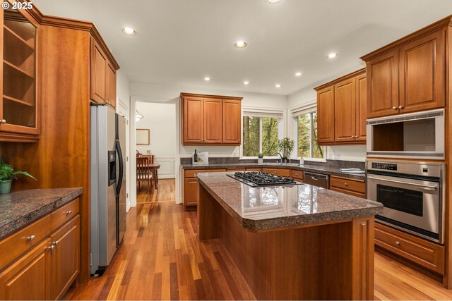 kitchen with a kitchen bar, sink, appliances with stainless steel finishes, a kitchen island, and dark hardwood / wood-style flooring