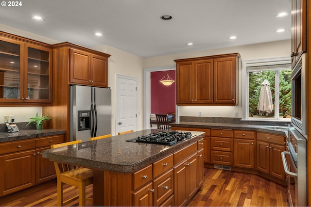 kitchen featuring a kitchen bar, appliances with stainless steel finishes, dark hardwood / wood-style flooring, sink, and a kitchen island