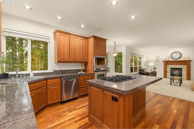 kitchen with appliances with stainless steel finishes, a breakfast bar, sink, hardwood / wood-style floors, and a center island