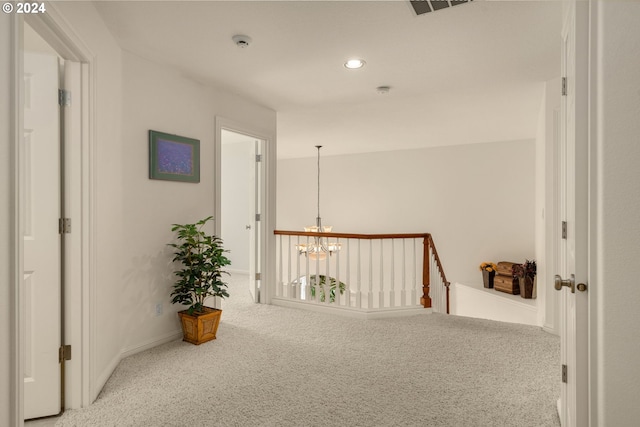 hall featuring carpet and a chandelier