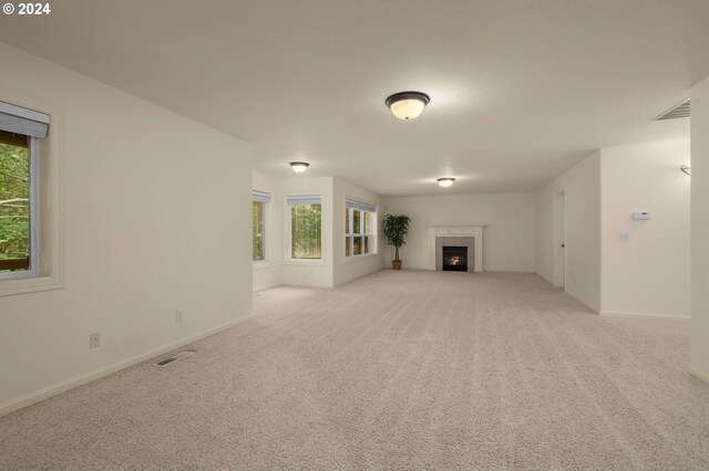 unfurnished living room featuring light carpet and a tile fireplace