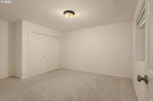 unfurnished bedroom with carpet flooring, a textured ceiling, and a closet