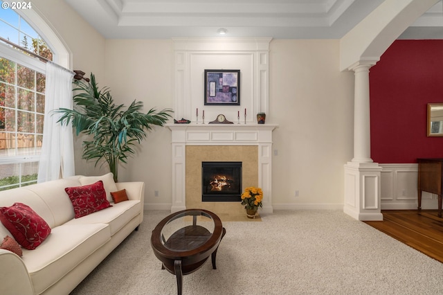 carpeted living room featuring a tile fireplace and ornate columns