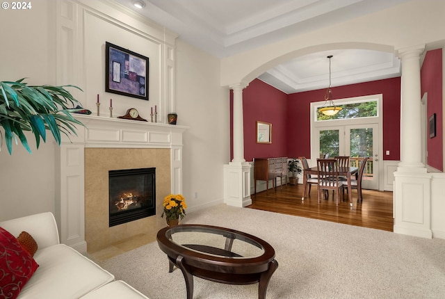 living room featuring a raised ceiling, a tile fireplace, and dark carpet