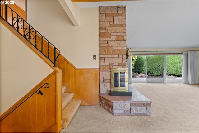 unfurnished living room featuring carpet flooring, stairs, a wainscoted wall, and wooden walls