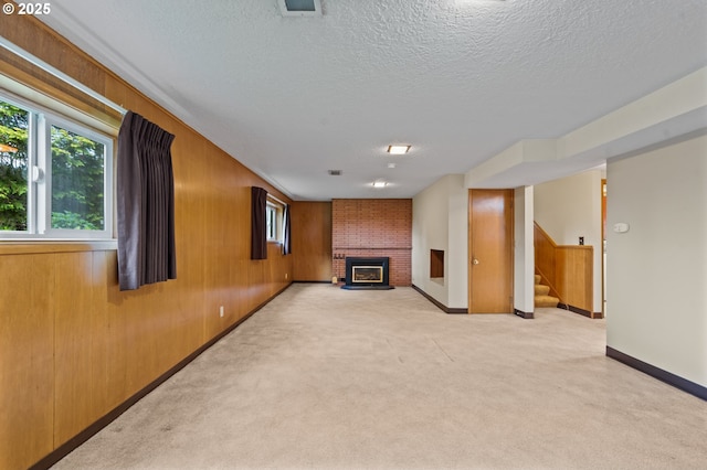 unfurnished living room featuring a brick fireplace, a textured ceiling, stairs, light carpet, and baseboards
