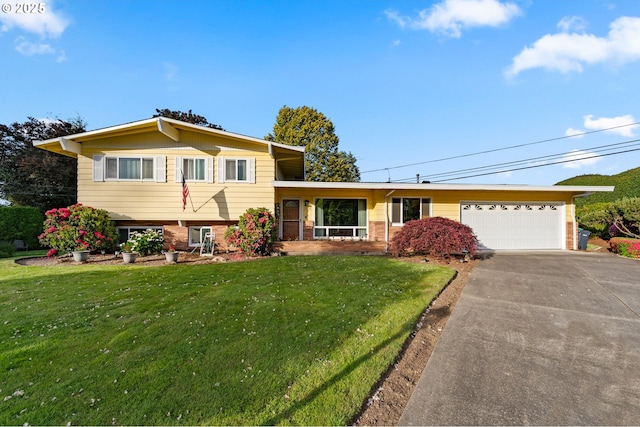 split level home featuring a garage, driveway, a front lawn, and brick siding