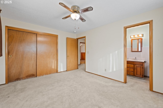unfurnished bedroom featuring a sink, a closet, light colored carpet, and ensuite bath
