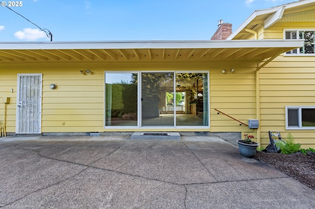 doorway to property featuring a patio area and a chimney
