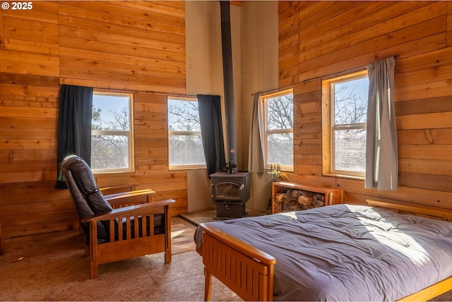 bedroom with a high ceiling, a wood stove, and wooden walls