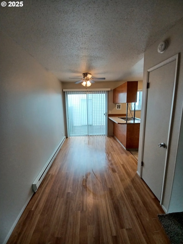 7720 SW Bel Aire Dr, Beaverton, OR 97008 - unfurnished living room with a baseboard radiator, wood finished floors, a textured ceiling, plenty of natural light, and ceiling fan