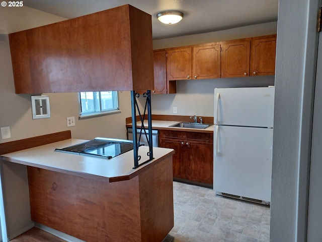 7720 SW Bel Aire Dr, Beaverton, OR 97008 - kitchen with freestanding refrigerator, a peninsula, brown cabinets, light countertops, and black stovetop