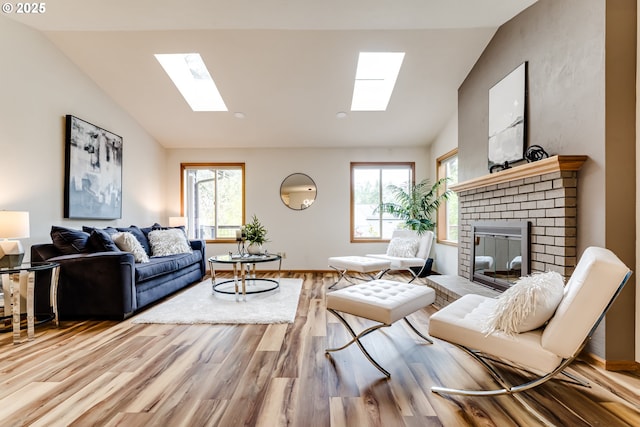 living area with wood finished floors, vaulted ceiling with skylight, a fireplace, and a wealth of natural light