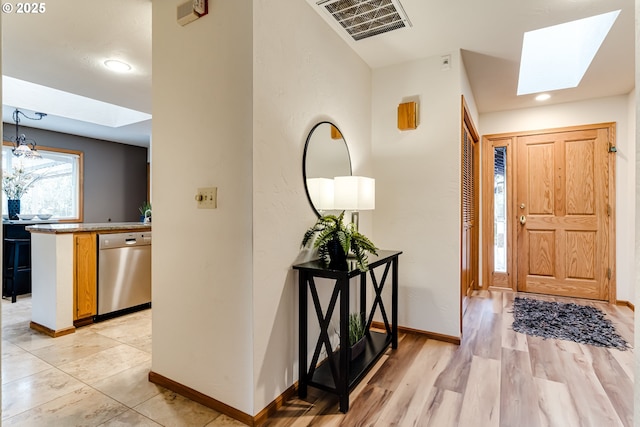 foyer with light wood finished floors, visible vents, baseboards, recessed lighting, and a skylight