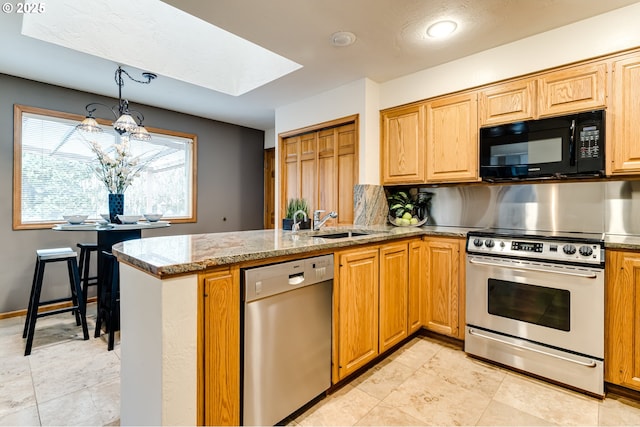 kitchen with light stone countertops, a peninsula, a skylight, a sink, and stainless steel appliances