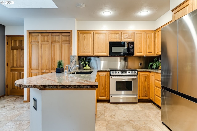 kitchen featuring a peninsula, a skylight, stone countertops, a sink, and appliances with stainless steel finishes