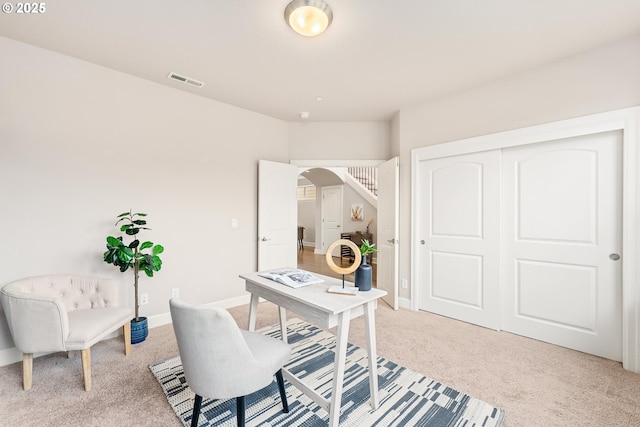 office with visible vents, arched walkways, light colored carpet, and baseboards