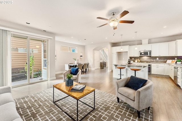 living room with arched walkways, recessed lighting, a wealth of natural light, and wood finished floors