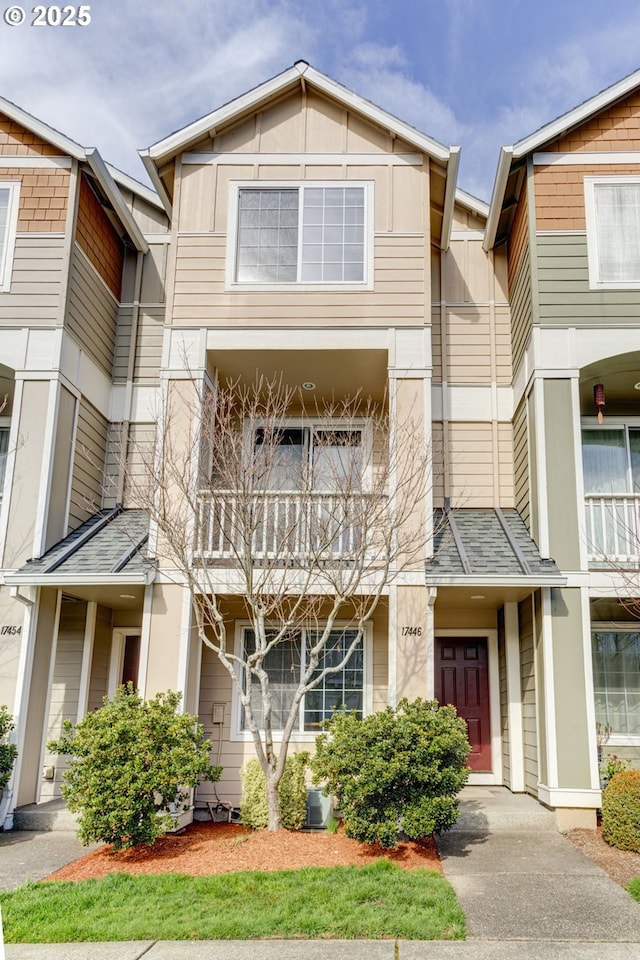 townhome / multi-family property featuring a balcony, board and batten siding, and a shingled roof