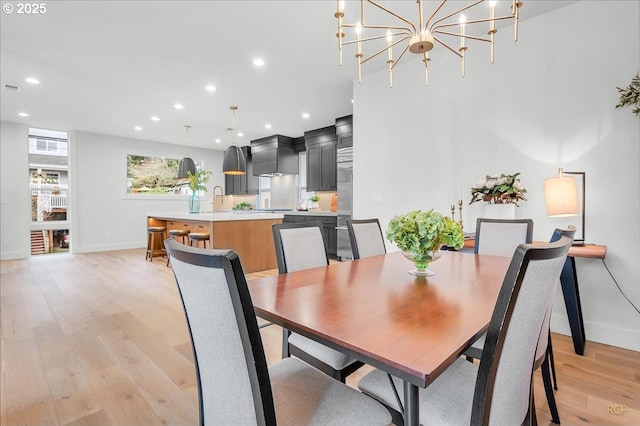 dining area featuring light hardwood / wood-style flooring, a notable chandelier, and sink