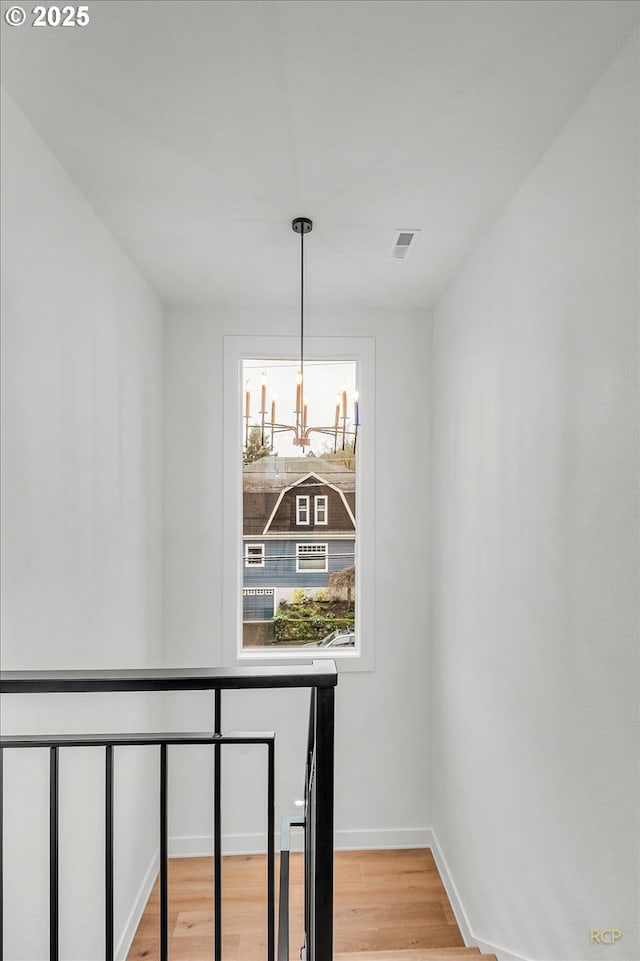 staircase with hardwood / wood-style flooring and a notable chandelier