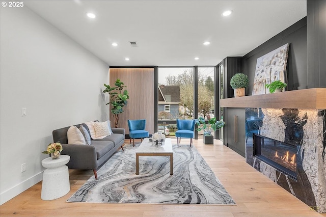 living room with a wall of windows, a tile fireplace, and light hardwood / wood-style flooring