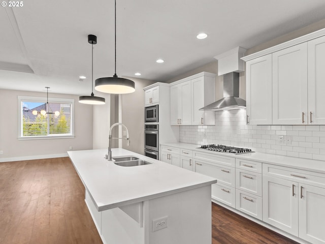 kitchen with pendant lighting, sink, stainless steel appliances, white cabinets, and a center island with sink