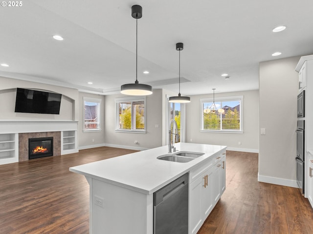 kitchen featuring appliances with stainless steel finishes, sink, white cabinets, hanging light fixtures, and a kitchen island with sink