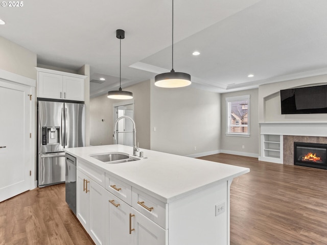 kitchen with a kitchen island with sink, sink, white cabinets, and appliances with stainless steel finishes