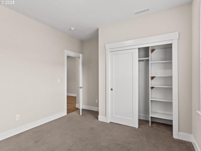 unfurnished bedroom featuring dark carpet and a closet