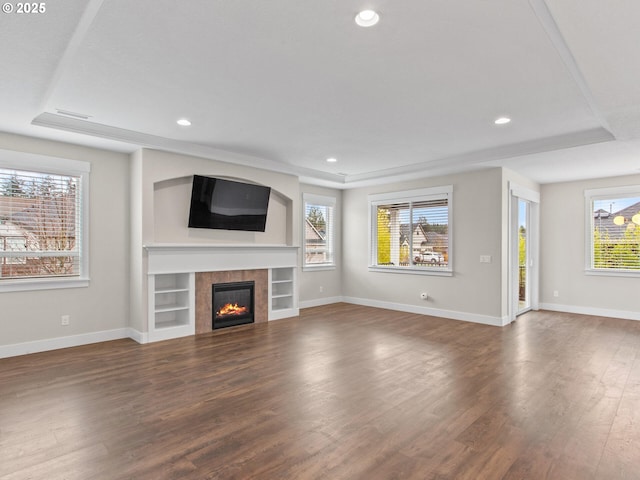 unfurnished living room featuring dark wood-type flooring, a fireplace, and a raised ceiling