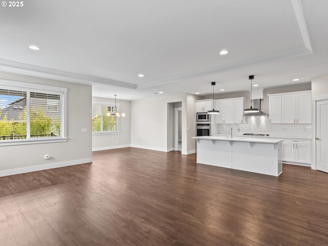 unfurnished living room with dark hardwood / wood-style flooring, sink, a tray ceiling, and an inviting chandelier