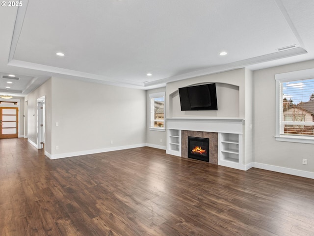 unfurnished living room featuring a tiled fireplace, plenty of natural light, and dark hardwood / wood-style floors