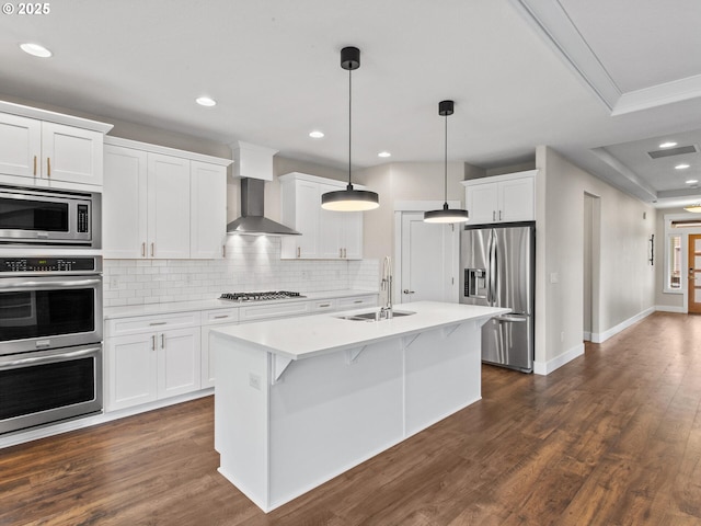 kitchen featuring sink, hanging light fixtures, stainless steel appliances, white cabinets, and wall chimney exhaust hood