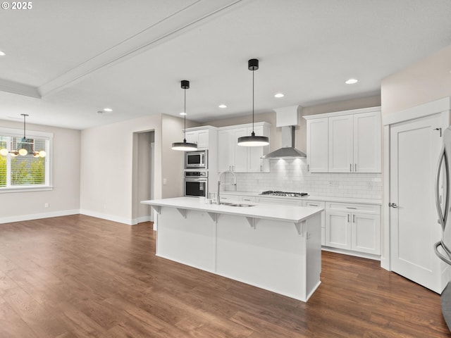 kitchen with white cabinetry, appliances with stainless steel finishes, sink, and wall chimney range hood